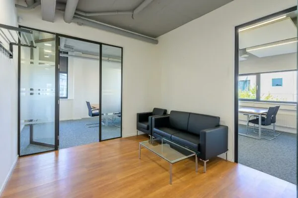 Wachtruimte met zwarte zitbanken en glazen vergaderruimtes in een kantoor aan de K.P. van der Mandelelaan.